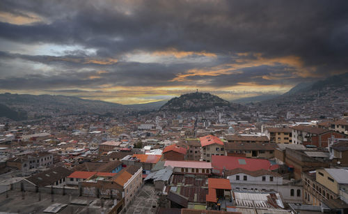 Panoramic view of quito downtown with the panecillo hill in the background during a cloudy sunset