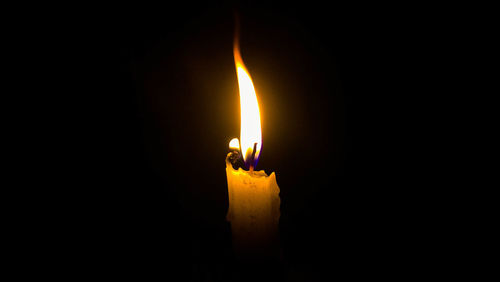 Close-up of illuminated candle against black background