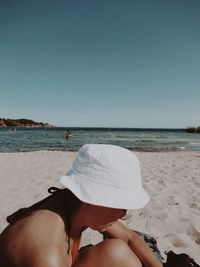 Man wearing hat on beach against clear sky