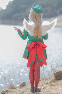 Rear view of woman in angel costume standing by lake