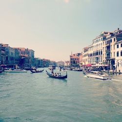 Boats in canal with buildings against sky