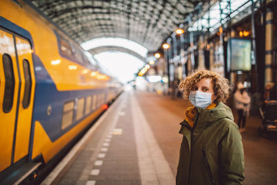 Portrait of woman wearing a mask standing at railroad station