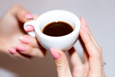 Cropped hands holding black coffee against gray background