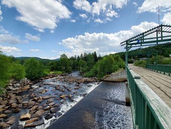 Bridge over river waterfalls against sky