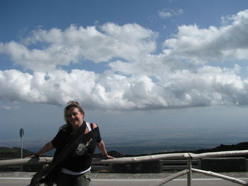 Portrait of smiling young woman standing in sea against sky