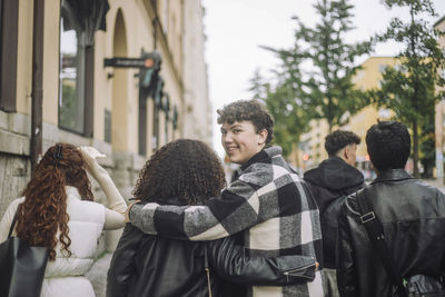 Portrait of smiling boy with arm around female friend walking at street