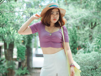 Young woman wearing hat standing against plants