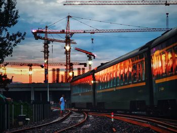 Train on railroad tracks against sky at sunset
