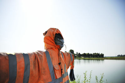 Man standing by lake against clear sky