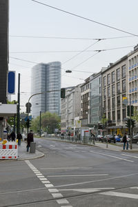 Road by buildings in city against sky