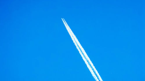 Low angle view of vapor trail against blue sky