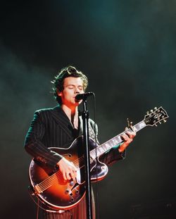 Man playing guitar while singing on microphone