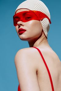 Low angle view of young woman wearing hat against blue background