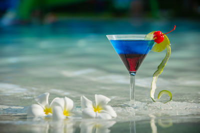 Drink in martini glass and flowers by fountain