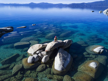 Woman looking at view while sitting on rock at lake tahoe