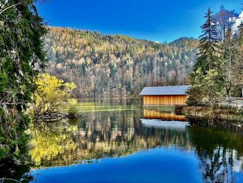 Scenic view of lake with boathouse in forest against sky