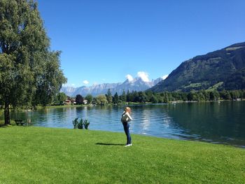 Woman standing on grassy field against lake