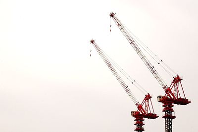 Low angle view of cranes against clear sky