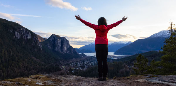 Rear view of man standing on mountain against sky