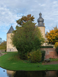 Trees by historic building against sky