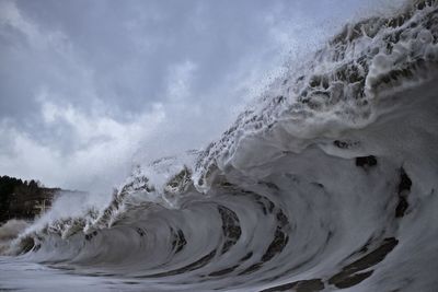 Panoramic view of waves splashing on shore against sky