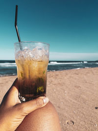 Glass of water on beach against sky