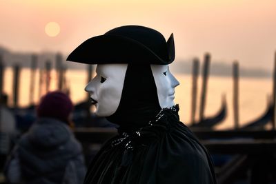 Close-up of person wearing mask during sunset