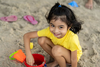 Portrait of cute girl playing on sand at beach