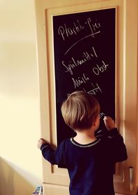 Boy writing on blackboard at home