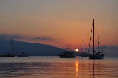 Sailboats sailing in sea against sky during sunset