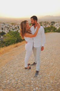 Young couple looking each other face to face while standing in city at sunset