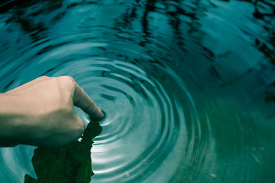 Cropped hand of person touching water