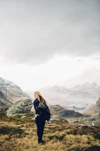 Young woman standing by mountain against sky