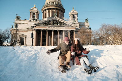 Couple have fun in snow against saint isaac cathedral 