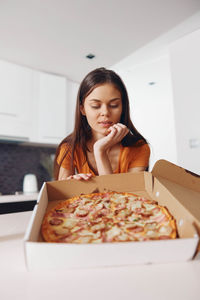 Portrait of young woman having food at home