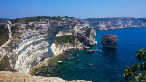 Panoramic view of sea and rocks against clear blue sky