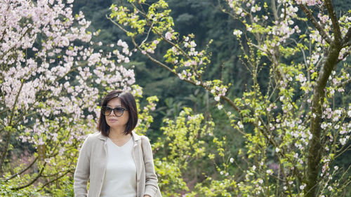 Woman standing by plants against trees