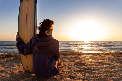 Rear view of woman looking at sea during sunset