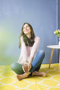 Smiling woman sitting on floor holding glass of juice