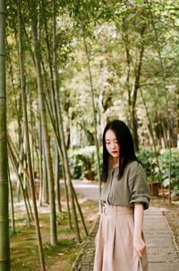 Woman standing on boardwalk amidst plants