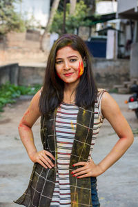 Portrait of smiling young woman with powder paint on face during holi