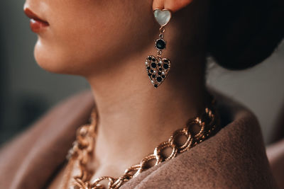 A gold chain hanging on a woman's neck and an earring in the shape of a heart. beautiful jewelry