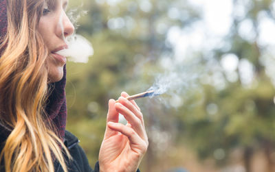 Portrait of woman smoking marijuana joint outdoors