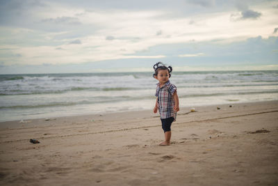 Full length of boy on beach against sky