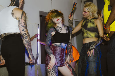 Tattooed woman dancing with non-binary friends at nightclub