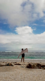 Rear view of women standing on beach against sky