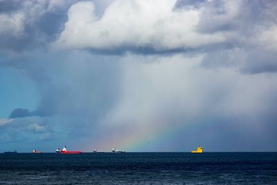 Sailboat sailing in sea against cloudy sky