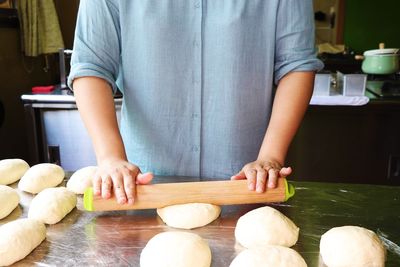 Midsection of woman rolling dough at home