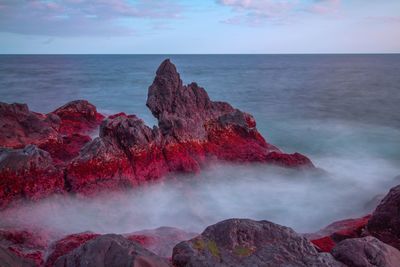 Rock formations in sea against sky