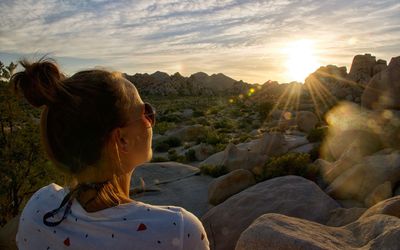 Rear view of woman against sky during sunset